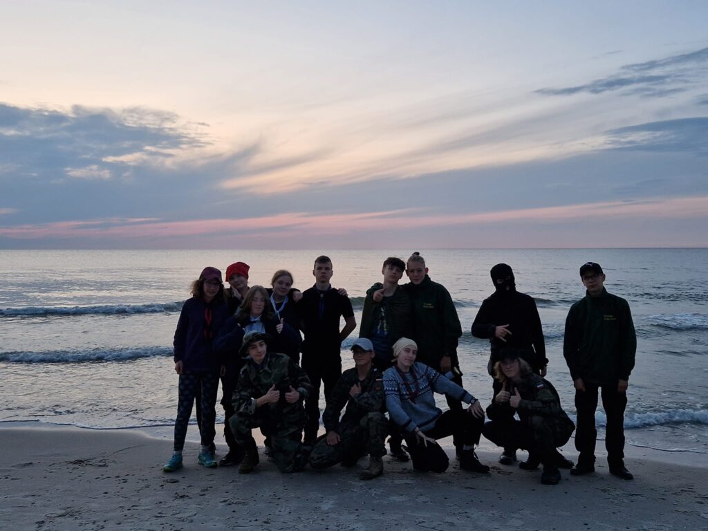 Harcerze i harcerki na tle zachodącego Słońca na plaży w Pogorzelicy